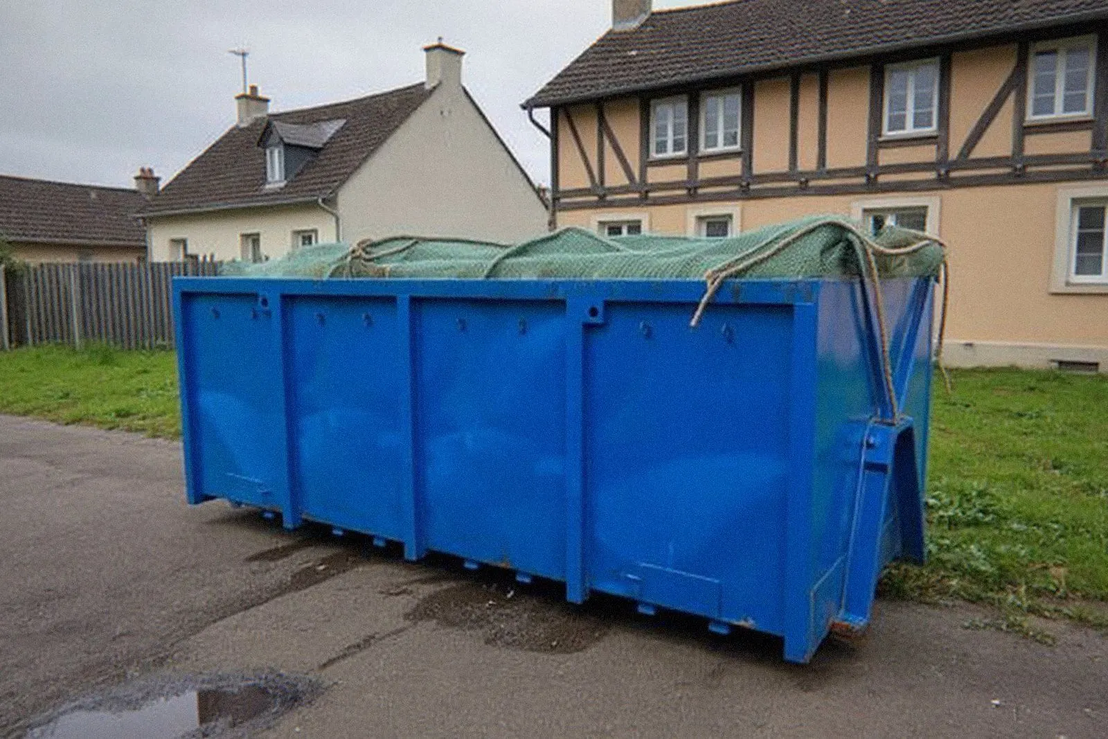 Benne bleue pleine couverte d'un filet près de Haguenau, réponses aux questions sur la location de benne